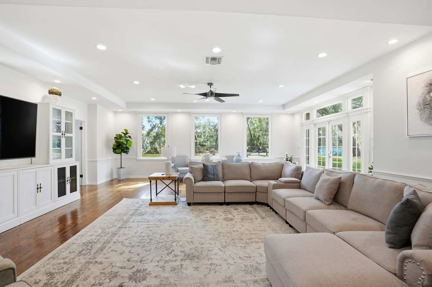 The great room inside the estate house — a large sectional, hardwood floors, and French doors opening toward the grounds